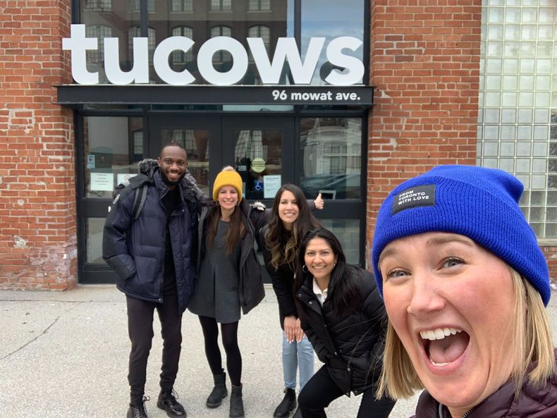 A group of happy employees posing at the front entrance of Tucows headquarters
